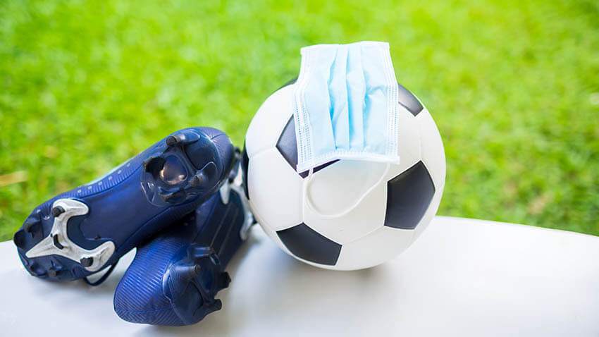 Soccer_ball_with_cleats_and_mask_near_green_field